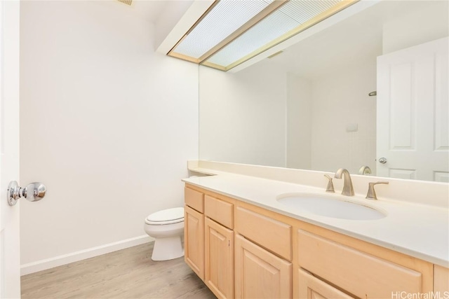 bathroom featuring vanity, toilet, a skylight, and hardwood / wood-style floors