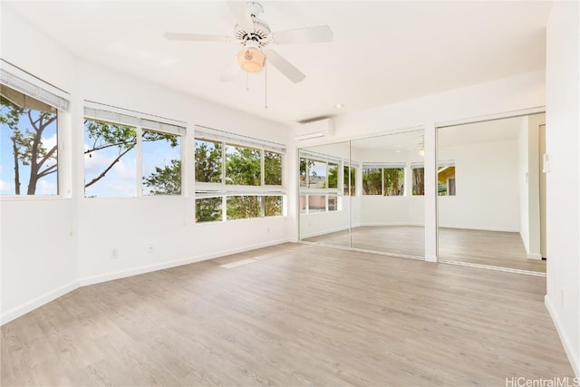 unfurnished sunroom with ceiling fan, plenty of natural light, and a wall unit AC