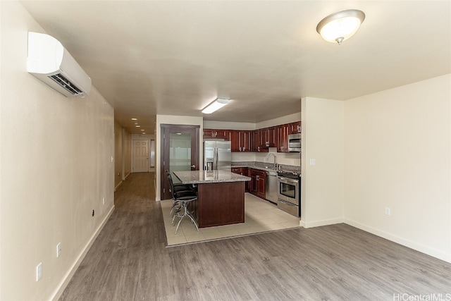 kitchen featuring a kitchen island, a breakfast bar, sink, stainless steel appliances, and a wall unit AC