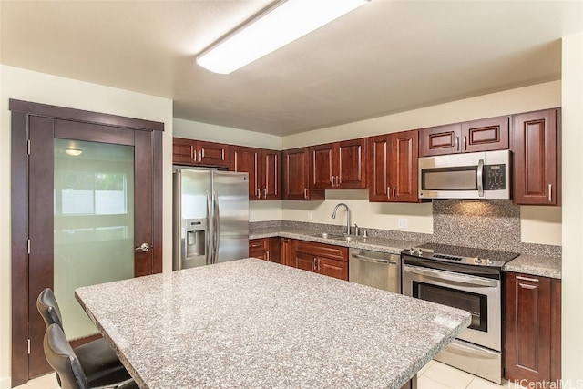 kitchen with appliances with stainless steel finishes, sink, and a breakfast bar area