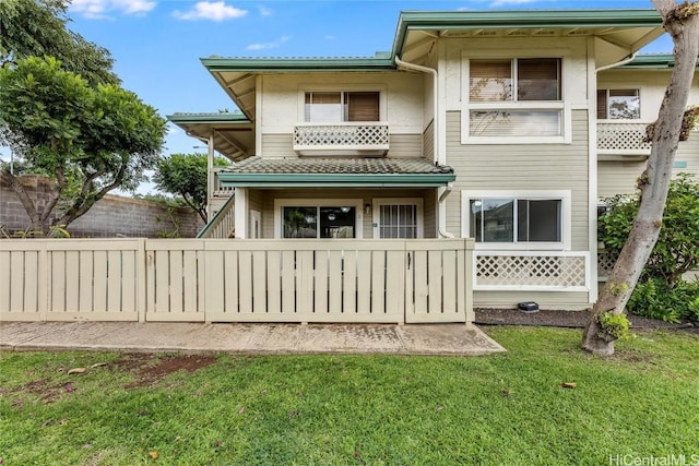 back of property featuring a balcony and a lawn