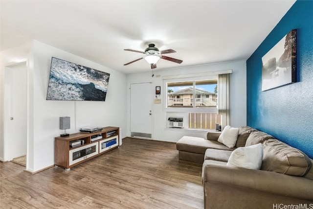 living room with heating unit, wood-type flooring, and ceiling fan