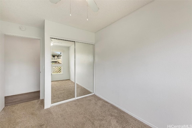 unfurnished bedroom featuring ceiling fan, carpet floors, a textured ceiling, and a closet