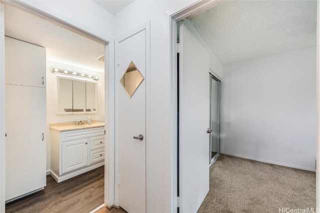 hallway with hardwood / wood-style floors, sink, and a textured ceiling