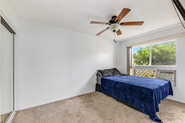 bedroom featuring ceiling fan, a wall unit AC, light colored carpet, and a textured ceiling