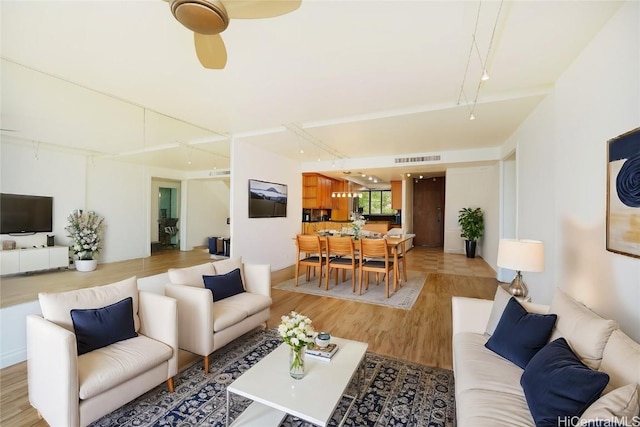 living area with visible vents, ceiling fan, and light wood finished floors