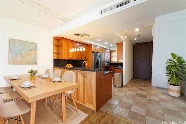 kitchen with stainless steel fridge, visible vents, dark countertops, a peninsula, and open shelves