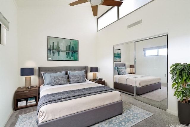 carpeted bedroom featuring a closet, visible vents, a towering ceiling, ceiling fan, and baseboards