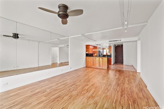 unfurnished living room featuring light wood finished floors, visible vents, baseboards, ceiling fan, and rail lighting