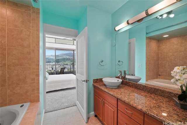 ensuite bathroom featuring tile patterned floors, tiled bath, connected bathroom, and vanity