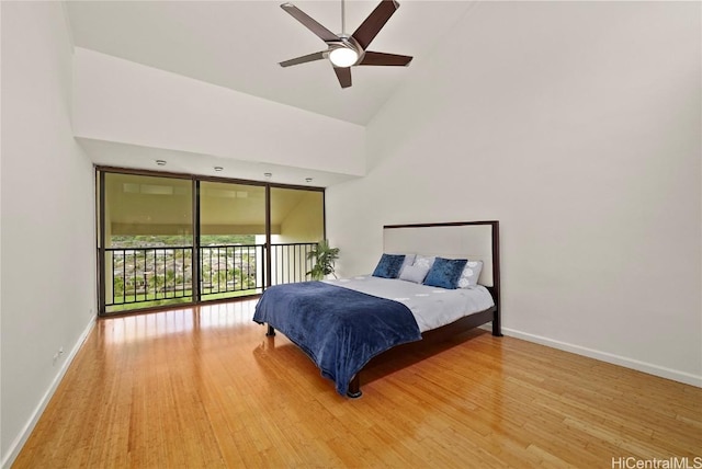 bedroom featuring high vaulted ceiling, access to outside, baseboards, and wood finished floors