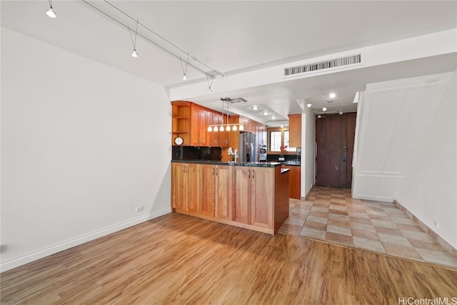 kitchen with stainless steel fridge, visible vents, dark countertops, a peninsula, and open shelves