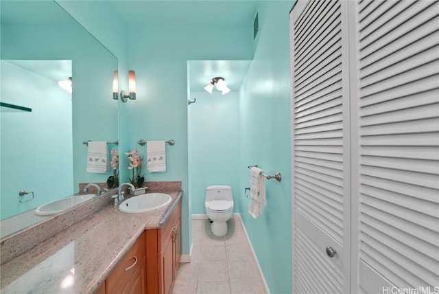 bathroom featuring tile patterned flooring, toilet, vanity, baseboards, and a closet