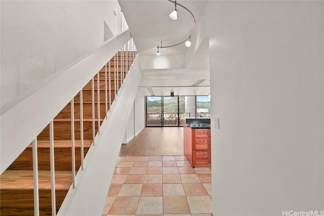 stairs featuring high vaulted ceiling, track lighting, and tile patterned floors