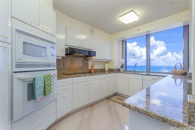 kitchen featuring light stone countertops, exhaust hood, white cabinets, and a water view