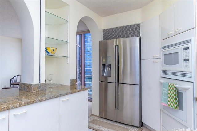 kitchen featuring light stone counters, white appliances, a textured ceiling, and white cabinets