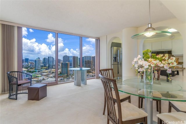 dining area featuring floor to ceiling windows, light colored carpet, and a textured ceiling