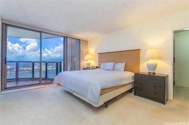 carpeted bedroom with a water view, access to outside, and a wall of windows