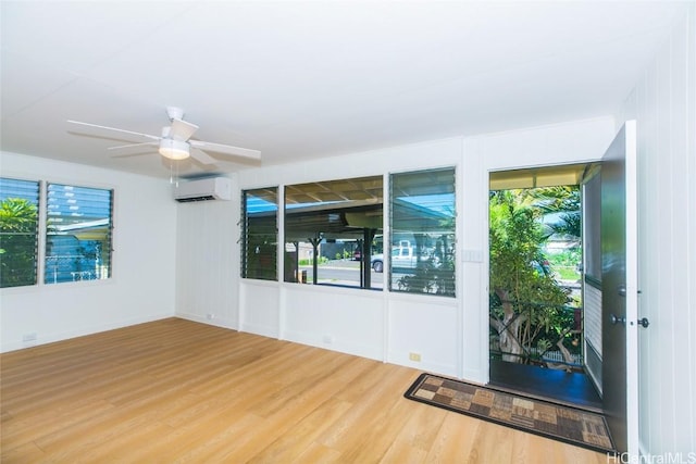 empty room with ceiling fan, an AC wall unit, wood-type flooring, and plenty of natural light