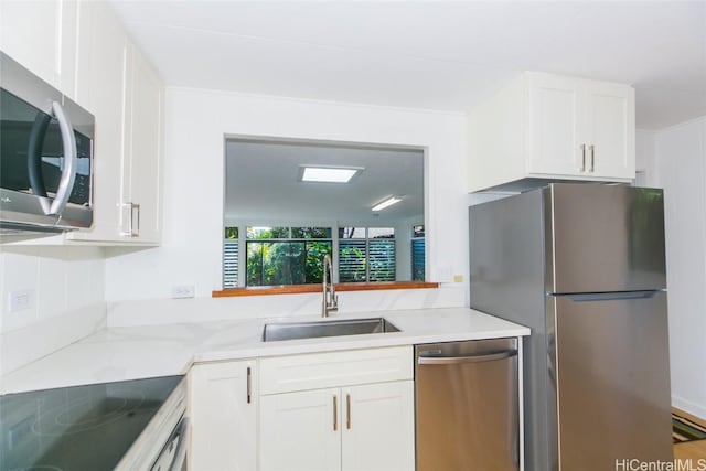 kitchen featuring appliances with stainless steel finishes, sink, white cabinets, and light stone counters