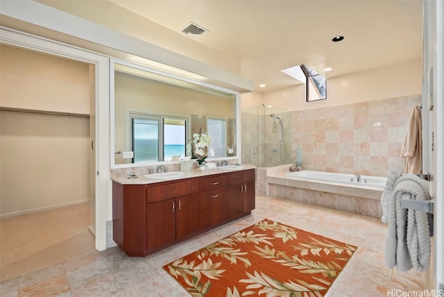 bathroom featuring vanity, separate shower and tub, and a skylight