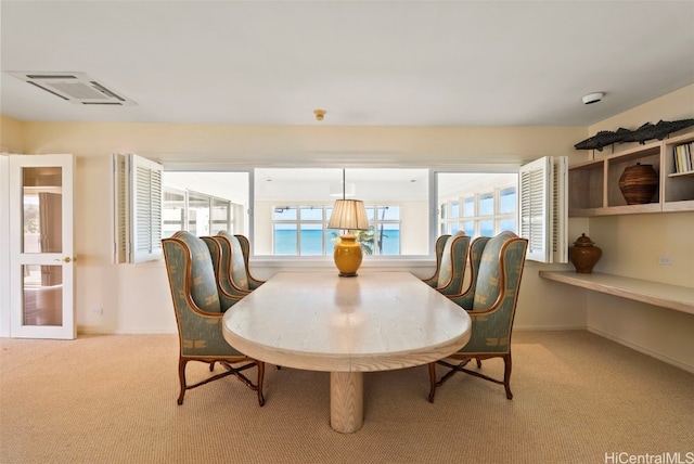 dining space with a water view and light carpet