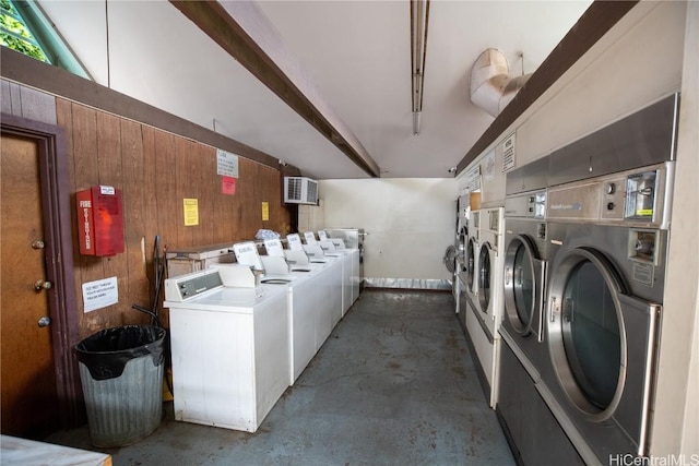 washroom featuring washing machine and clothes dryer and wood walls