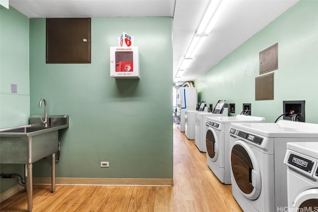 washroom featuring sink, light hardwood / wood-style flooring, and washing machine and dryer