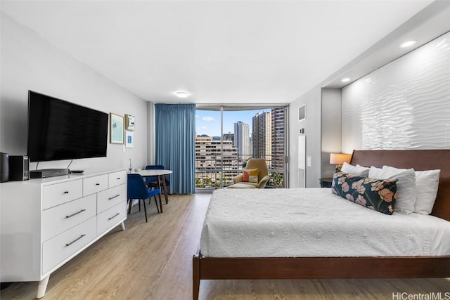 bedroom with a wall of windows and light hardwood / wood-style flooring