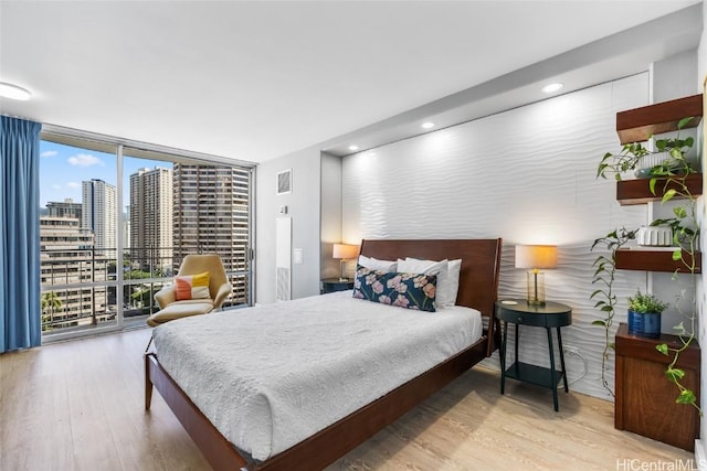 bedroom with floor to ceiling windows and light hardwood / wood-style flooring