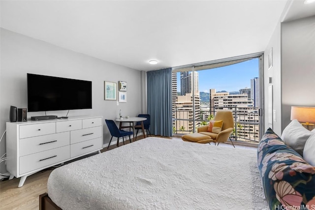 bedroom featuring a wall of windows, access to exterior, and light hardwood / wood-style floors