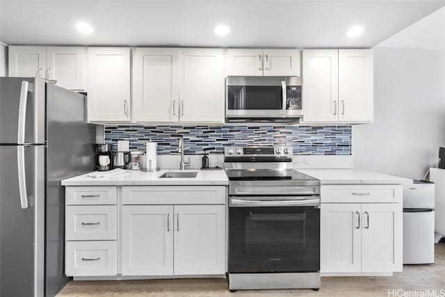 kitchen featuring sink, light hardwood / wood-style flooring, white cabinetry, backsplash, and stainless steel appliances