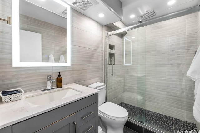 bathroom featuring walk in shower, toilet, tile walls, vanity, and backsplash