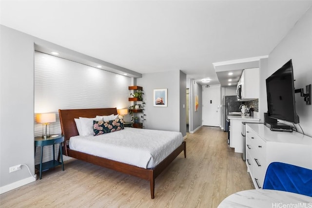 bedroom with stainless steel fridge and light hardwood / wood-style floors