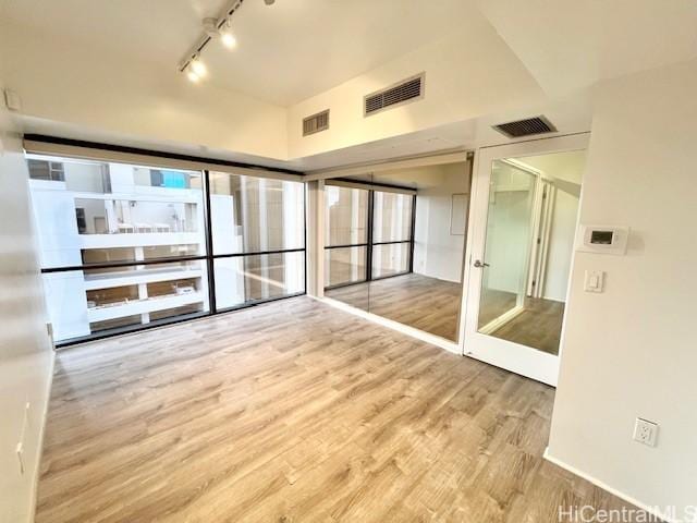 empty room featuring hardwood / wood-style flooring, rail lighting, and french doors