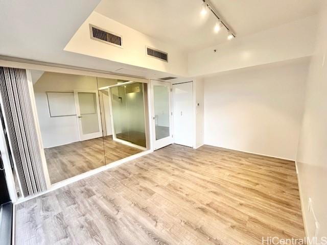 unfurnished bedroom featuring wood-type flooring and rail lighting