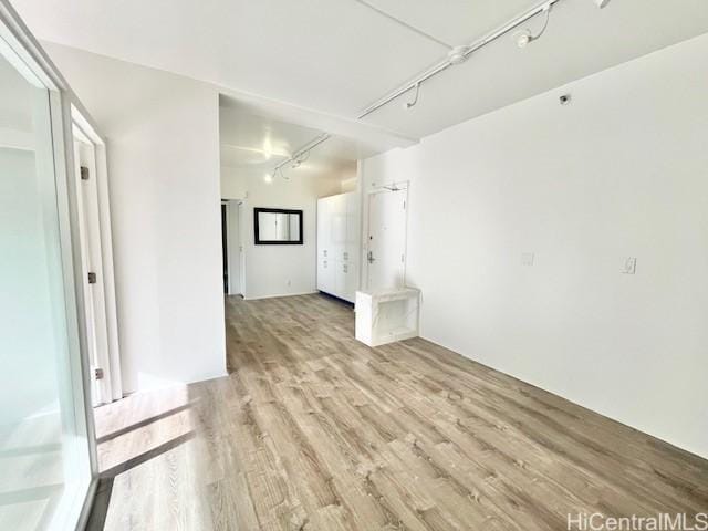 empty room featuring track lighting and light hardwood / wood-style floors