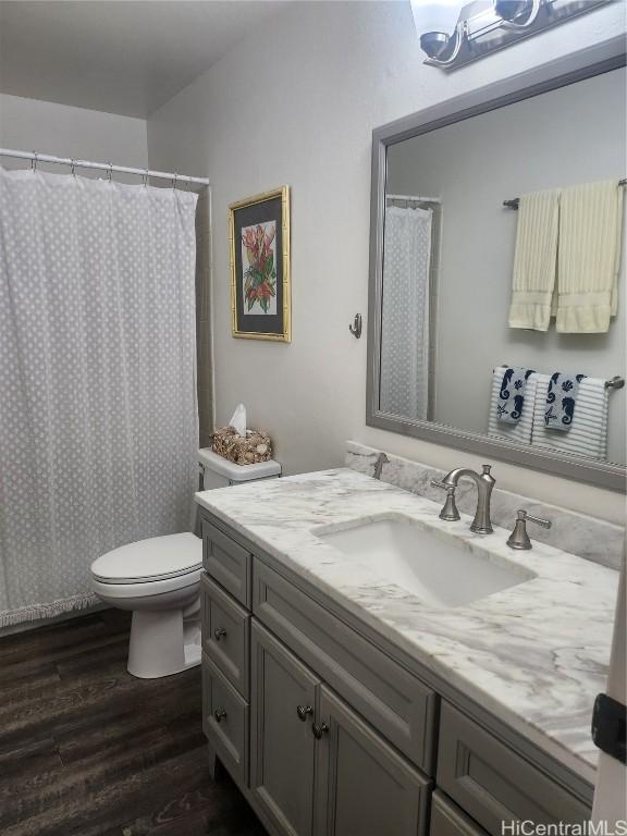 full bath with toilet, a shower with curtain, wood finished floors, and vanity