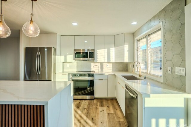 kitchen featuring sink, white cabinetry, tasteful backsplash, appliances with stainless steel finishes, and pendant lighting