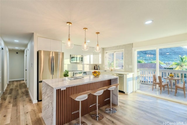 kitchen with appliances with stainless steel finishes, sink, a kitchen island, and white cabinets