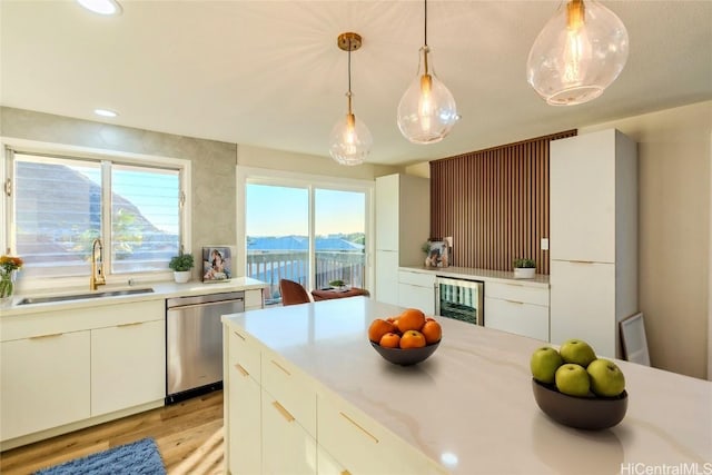 kitchen featuring dishwasher, sink, beverage cooler, hanging light fixtures, and plenty of natural light