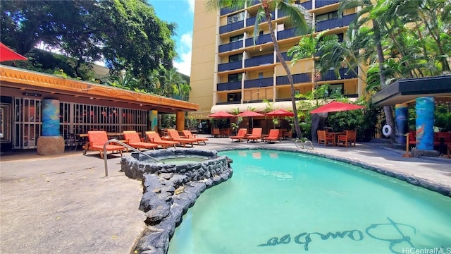 view of pool with a hot tub and a patio