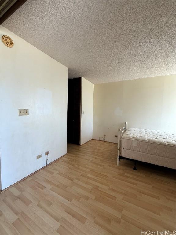 unfurnished bedroom featuring a textured ceiling and light hardwood / wood-style floors