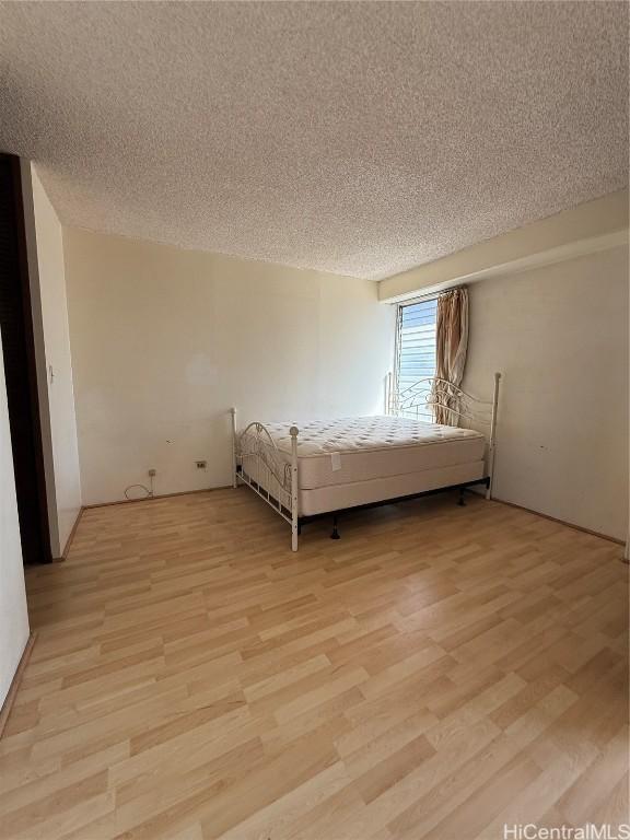 unfurnished bedroom with light hardwood / wood-style floors and a textured ceiling