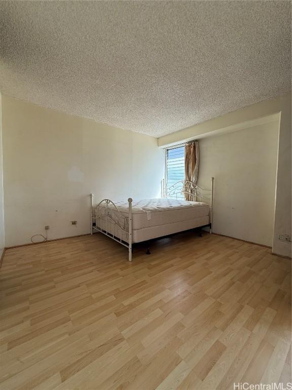 unfurnished bedroom with light hardwood / wood-style flooring and a textured ceiling