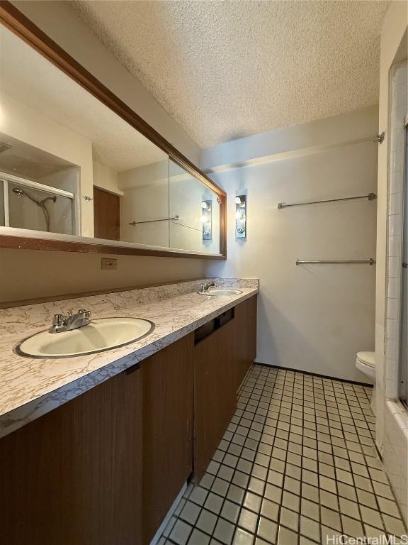 bathroom with vanity, toilet, a shower with door, tile patterned floors, and a textured ceiling