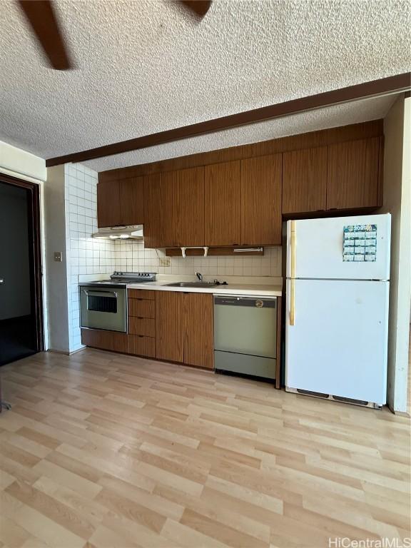 kitchen featuring tasteful backsplash, stainless steel appliances, a textured ceiling, and light wood-type flooring