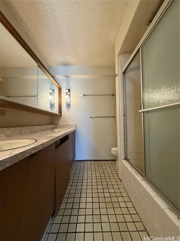 bathroom featuring vanity, tile patterned floors, a textured ceiling, and toilet