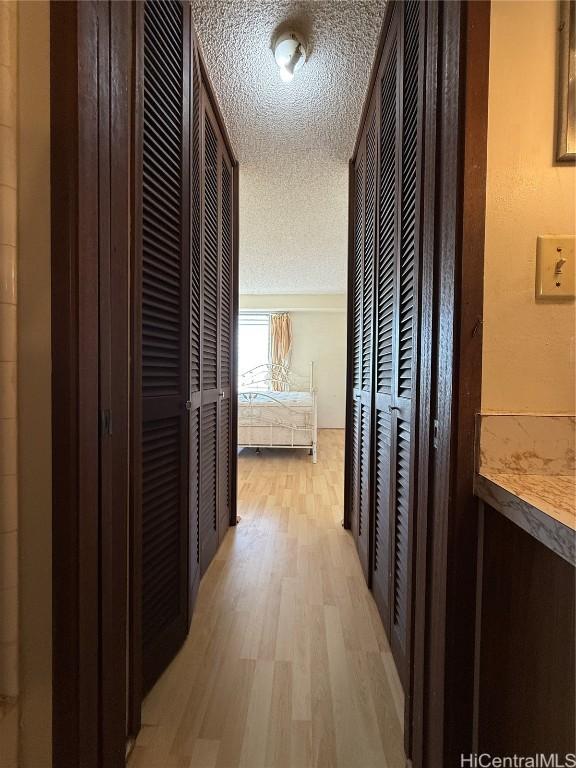 corridor featuring light hardwood / wood-style flooring and a textured ceiling