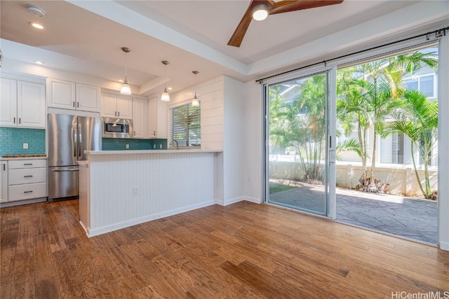 kitchen featuring white cabinetry, appliances with stainless steel finishes, kitchen peninsula, and plenty of natural light